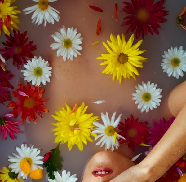 A woman submerged in a pool of water with flowers floating at the top, obscuring her nude figure.