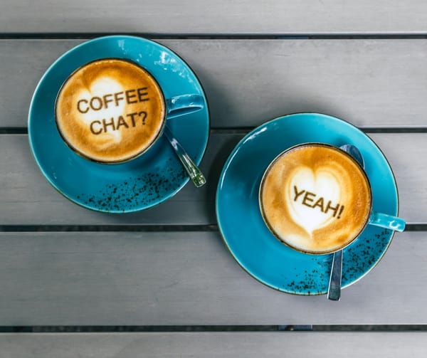 Two lattes with heart shaped art. One says "Coffee chat?" The other says "Yeah!"